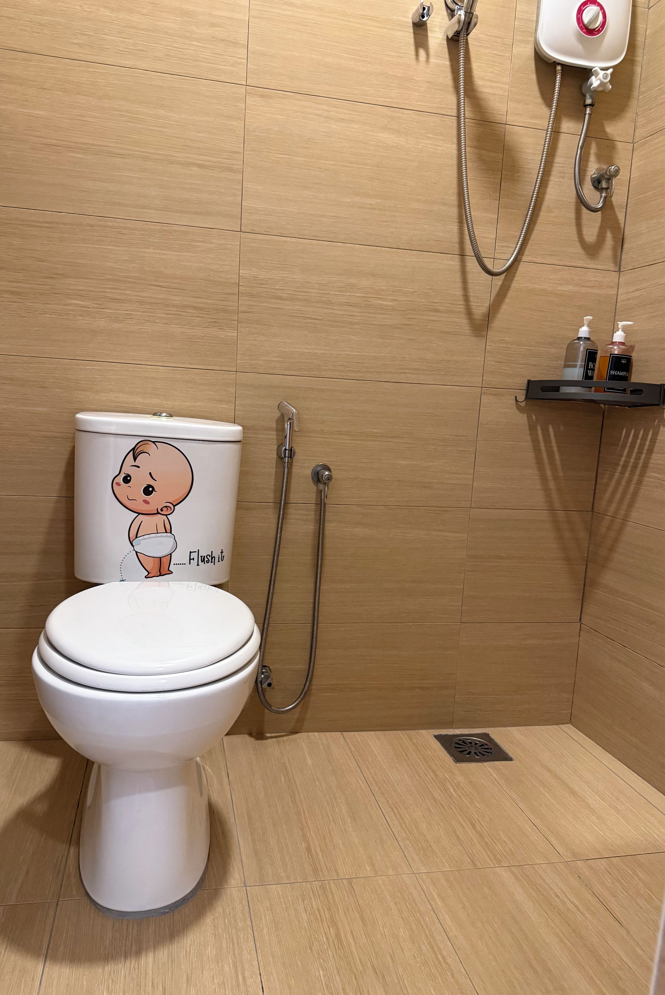 A bathroom with a toilet, a shower, and a shelf with toiletries.