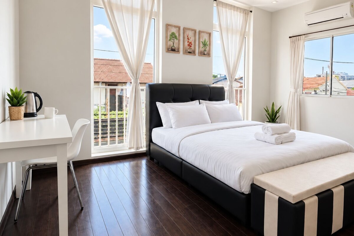A modern bedroom with a bed, a desk, and a view of the outside.
