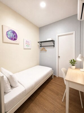 A single-bed room with a wooden floor, a white desk with a lamp, a hanging shelf, and two motivational posters on the wall. - The Backpackers Hut @ Jonker Melaka (Malacca City)