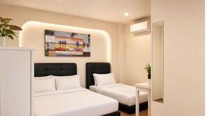 Habitación de hotel con dos camas, una mesita de noche, un espejo, un cuadro en la pared y una planta en maceta.