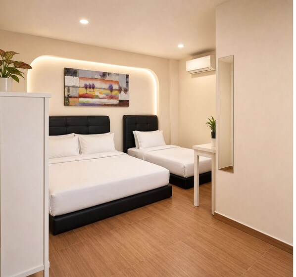 A hotel room with two beds, a bedside table, a mirror, a painting on the wall, and a potted plant. - The Backpackers Hut @ Jonker Melaka (Malacca City)