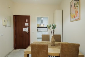 A dining area with a wooden table, wicker chairs, and a vase with branches.