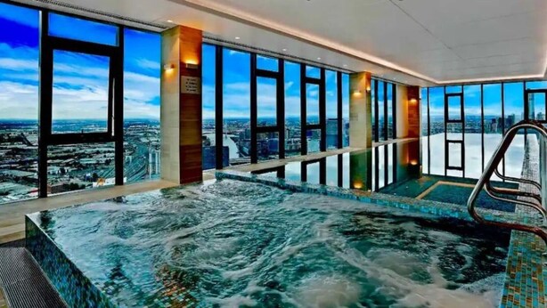 A modern indoor pool with a city view, large windows, and a clear sky. - Luxury apartment & free parking x1 (Southbank)