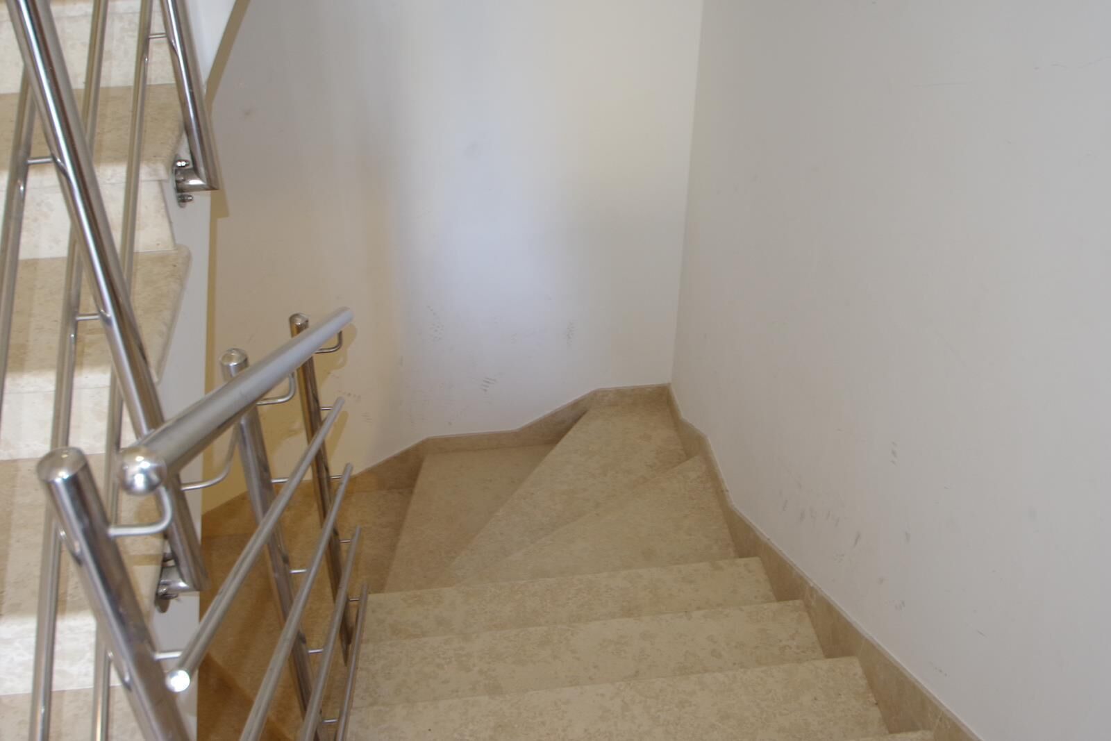 Un escalier avec des rampes en métal et des marches recouvertes d’un tapis beige.