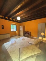 Una habitación amplia con una cama grande, una ventana, un radiador, un armario y un banco.