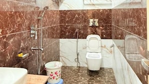A bathroom with a toilet, shower, and sink. - Hotel Mangalam (Varanasi)