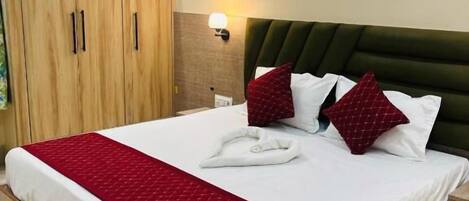 Une chambre d’hôtel avec un grand lit, une armoire en bois et une lampe fixée au mur.
