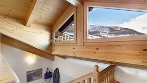 Een houten interieur met uitzicht op een besneeuwd landschap door een raam.