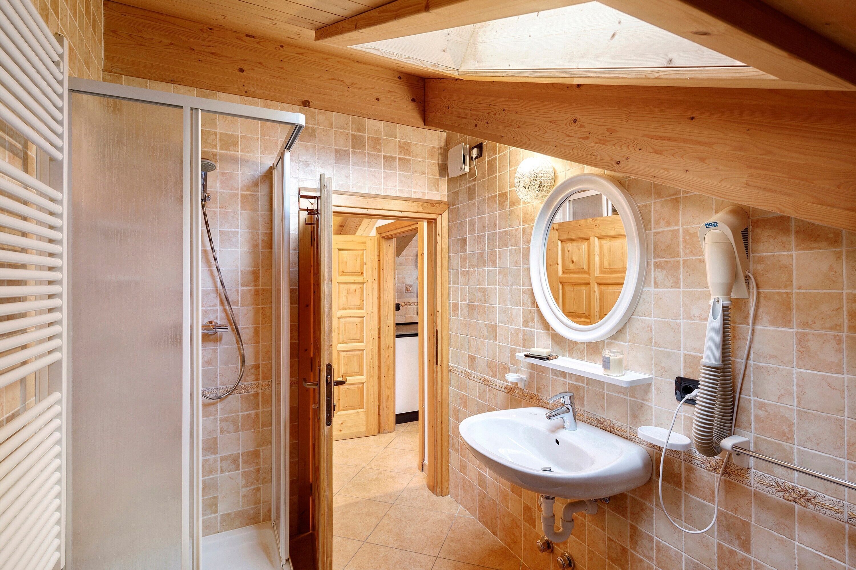 A bathroom with a shower, sink, and a hairdryer mounted on the wall.