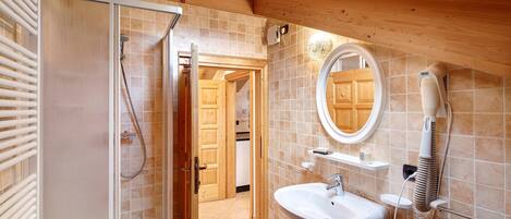 A bathroom with a shower, sink, and a hairdryer mounted on the wall.
