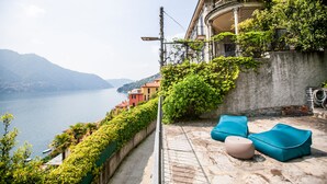 A terrace with outdoor seating, overlooking a body of water and mountains. - Appartamento Fioravante by Wonderful Italy (Moltrasio)