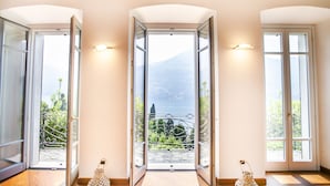 A hotel entrance with three open doors leading to balconies with views of greenery and a mountain. - Appartamento Fioravante by Wonderful Italy (Moltrasio)