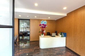 A reception desk with a logo, a vase of flowers, and a computer. - G8 Le Van Sy Hotel Saigon (Ho Chi Minh City)