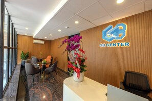 A reception area with a wooden panel wall, a logo for 'GB Center', a reception desk, and a potted orchid arrangement. - G8 Le Van Sy Hotel Saigon (Ho Chi Minh City)