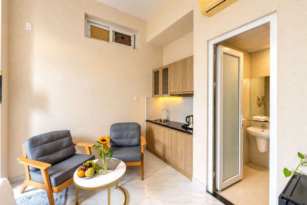 Un espacio habitable compacto con kitchenette, dos zonas de estar y un baño.