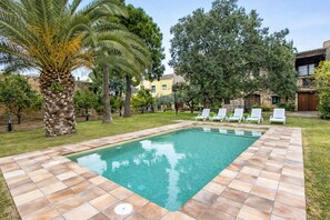 A rectangular pool with tiled edges, surrounded by grass and trees, with white lounge chairs and a palm tree. - Majestic history for 32 guests, 10km to the beach (Santa Oliva)