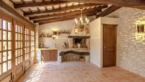 Una cocina rústica con paredes de piedra, vigas de madera, piso de baldosas y una lámpara de araña.