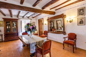 A dining room with a wooden table, chairs, a vase of flowers, a mirror, and a cabinet. - Majestic history for 32 guests, 10km to the beach (Santa Oliva)