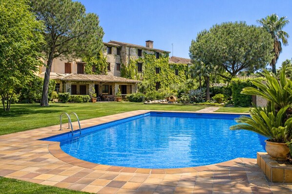 A swimming pool with a stone deck, surrounded by a well-maintained lawn and trees. - Majestic history for 32 guests, 10km to the beach (Santa Oliva)