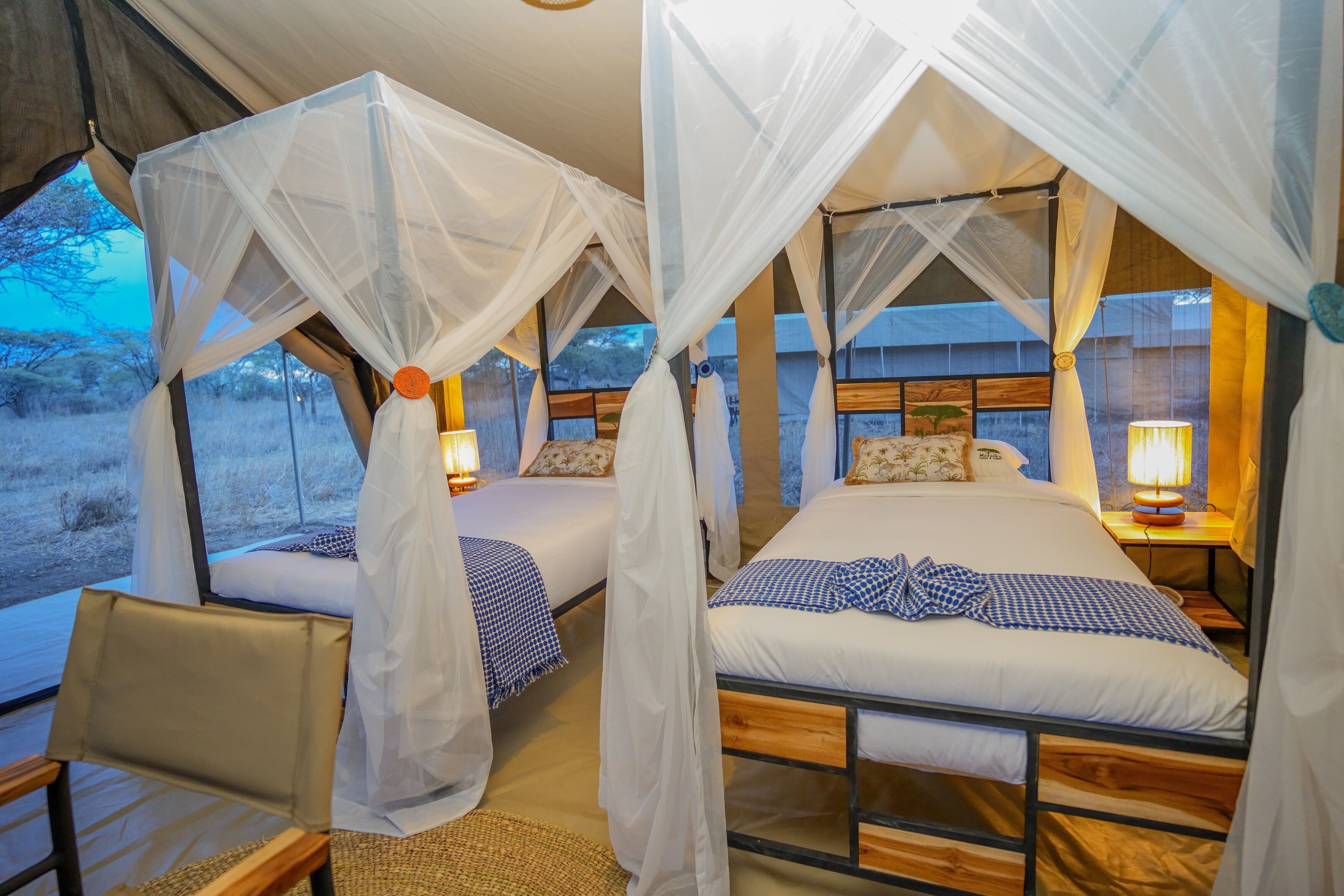A room with two beds, each with a canopy and bedside lamps.