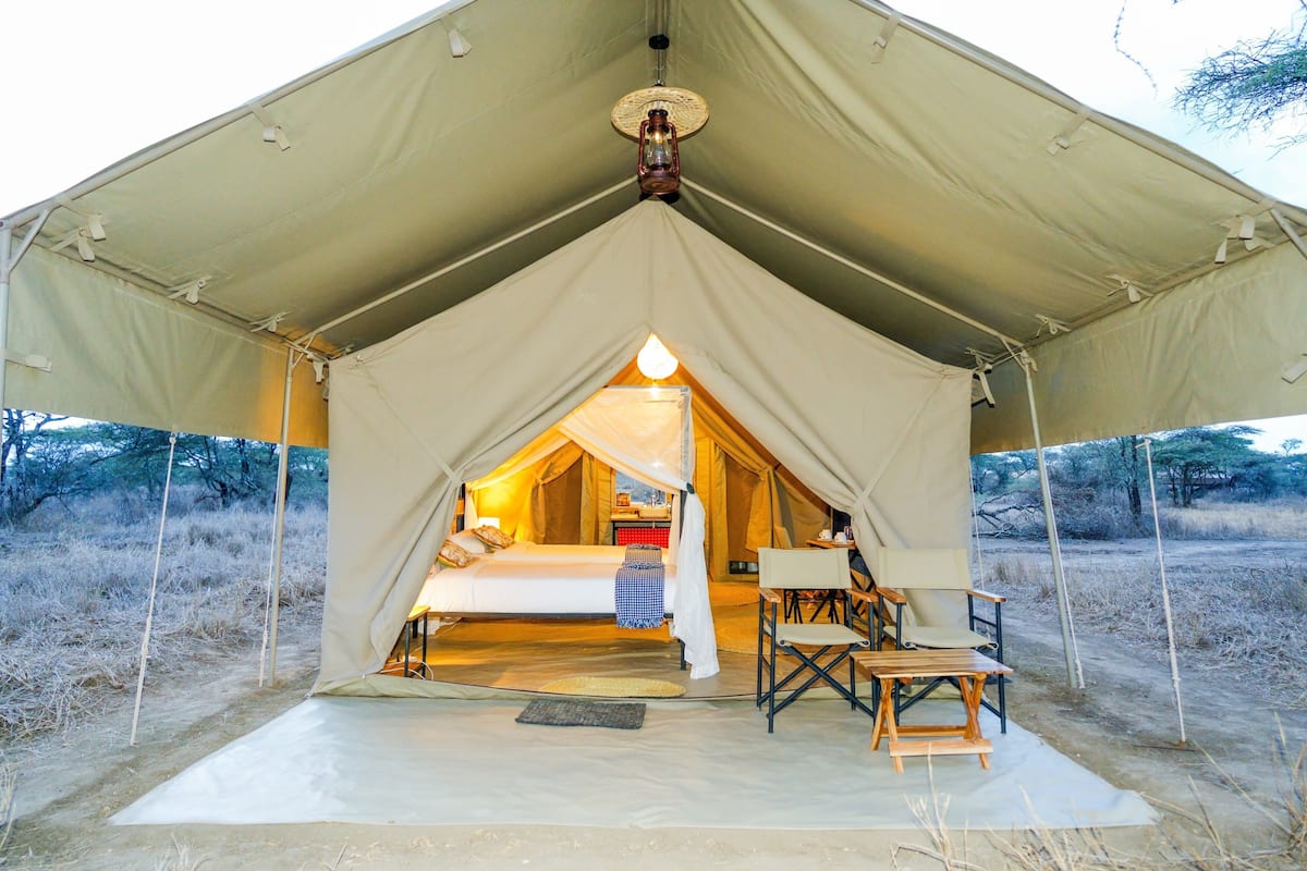 A tent with a bed, a table, and a chair inside.