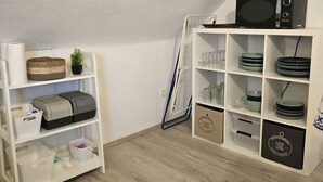 A neatly organized room with white shelving units containing kitchenware, a microwave, and storage bins. - Casa Lina - modern, central, in the countryside, close to trade fairs, Alsace & Karlsruhe, lovingly (Rheinstetten)