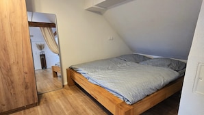 A bedroom with a wooden bed, a mirror, and a sloped ceiling. - Casa Lina - modern, central, in the countryside, close to trade fairs, Alsace & Karlsruhe, lovingly (Rheinstetten)