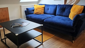 A cozy room with a blue sofa, a black coffee table, and a skylight above. - Casa Lina - modern, central, in the countryside, close to trade fairs, Alsace & Karlsruhe, lovingly (Rheinstetten)