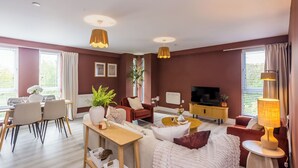A modern living room with a dining area, a sofa set, a TV, and a lamp.