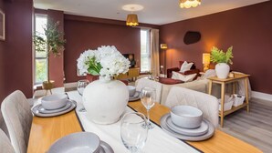 A modern dining area with a wooden table set for a meal, surrounded by comfortable seating.