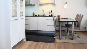 Une cuisine moderne avec des meubles blancs, un plan de travail noir et un coin repas comprenant une table et des chaises.