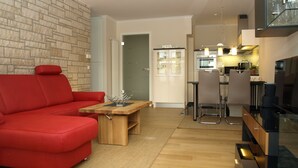 Un salon moderne avec un canapé rouge, une table basse en bois et un coin cuisine comprenant un ensemble de salle à manger.