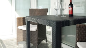 Un balcon avec une table, deux chaises et une bouteille de vin.