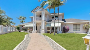 A two-story house with a covered porch, a driveway, and a well-maintained lawn. - Villa Maria 4BRM Home (Clear Island Waters)
