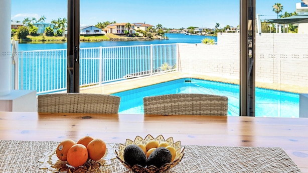 A view from a balcony overlooking a swimming pool with a table in the foreground featuring a bowl of fruit. - Villa Maria 4BRM Home (Clear Island Waters)