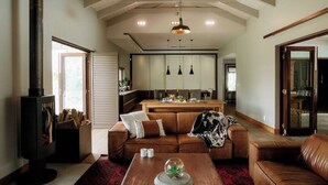Una sala de estar moderna con chimenea, sofá de cuero, mesa de centro de madera e iluminación colgante.