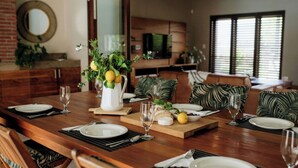 Un comedor con una mesa de madera dispuesta para una comida, que incluye una jarra de limones, un cuenco de aceitunas y un plato de queso.