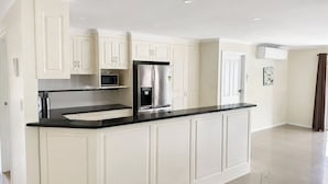 A modern kitchen with white cabinetry, a black countertop, and stainless steel appliances. - Relaxed Mount Gambier home with backyard (Mount Gambier)