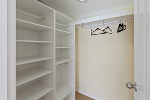 A walk-in closet with multiple shelves and a door with hangers.