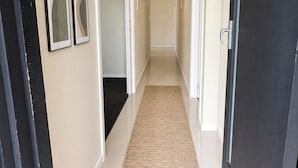 A hallway with a carpet, framed pictures on the wall, and a door on the right. - Relaxed Mount Gambier home with backyard (Mount Gambier)