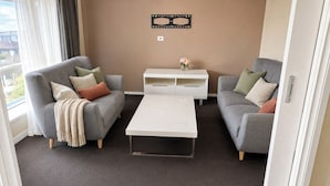 A living room with two grey sofas, a white coffee table, and a white sideboard. - Relaxed Mount Gambier home with backyard (Mount Gambier)
