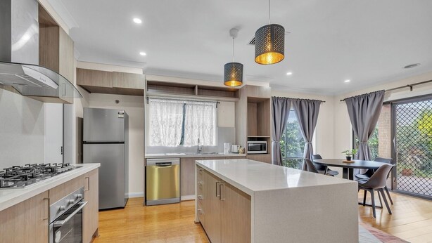 Una cocina moderna con una isla central, electrodomésticos integrados y un comedor con vistas.