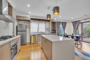 Una cocina moderna con una isla central, electrodomésticos integrados y un comedor con vistas.