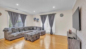 Una sala de estar con un sofá seccional, una mesa de centro y un televisor de pantalla plana.