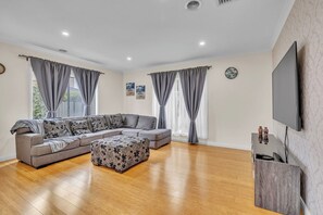 Una sala de estar con un sofá seccional, una mesa de centro y un televisor de pantalla plana.