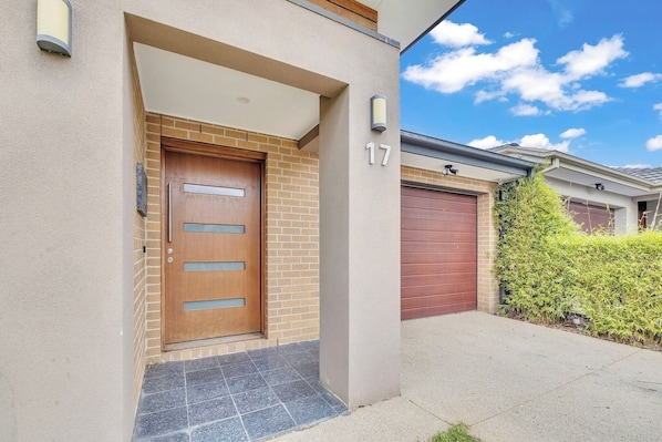 A modern house with a wooden front door, a garage, and a number '17' on the wall.