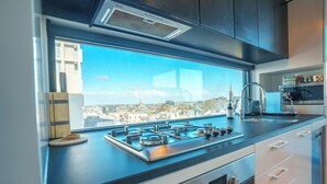 Uma cozinha moderna com fogão a gás, uma janela grande com vista para a cidade e forno embutido.
