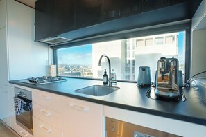 Une cuisine moderne dotée d’une grande fenêtre, d’une cuisinière encastrée, d’un évier et d’une machine à café.