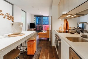 Een moderne keuken met een ruime gootsteen, een eethoek met tafel en stoelen, en uitzicht op de stad door grote ramen.