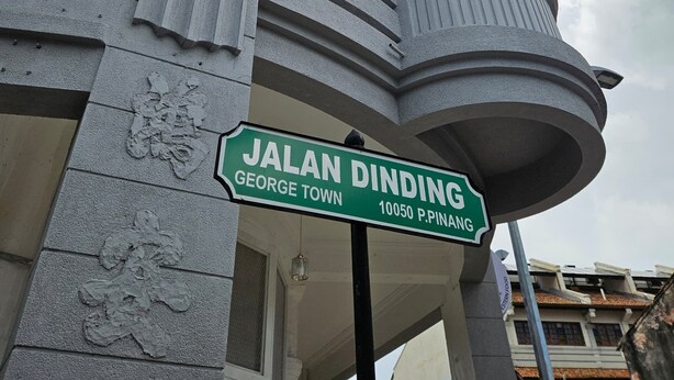 A building with a curved facade, a window, and a street sign reading "JALAN DINDING George Town 10050 P. PINANG". - KITA Hostel (George Town)